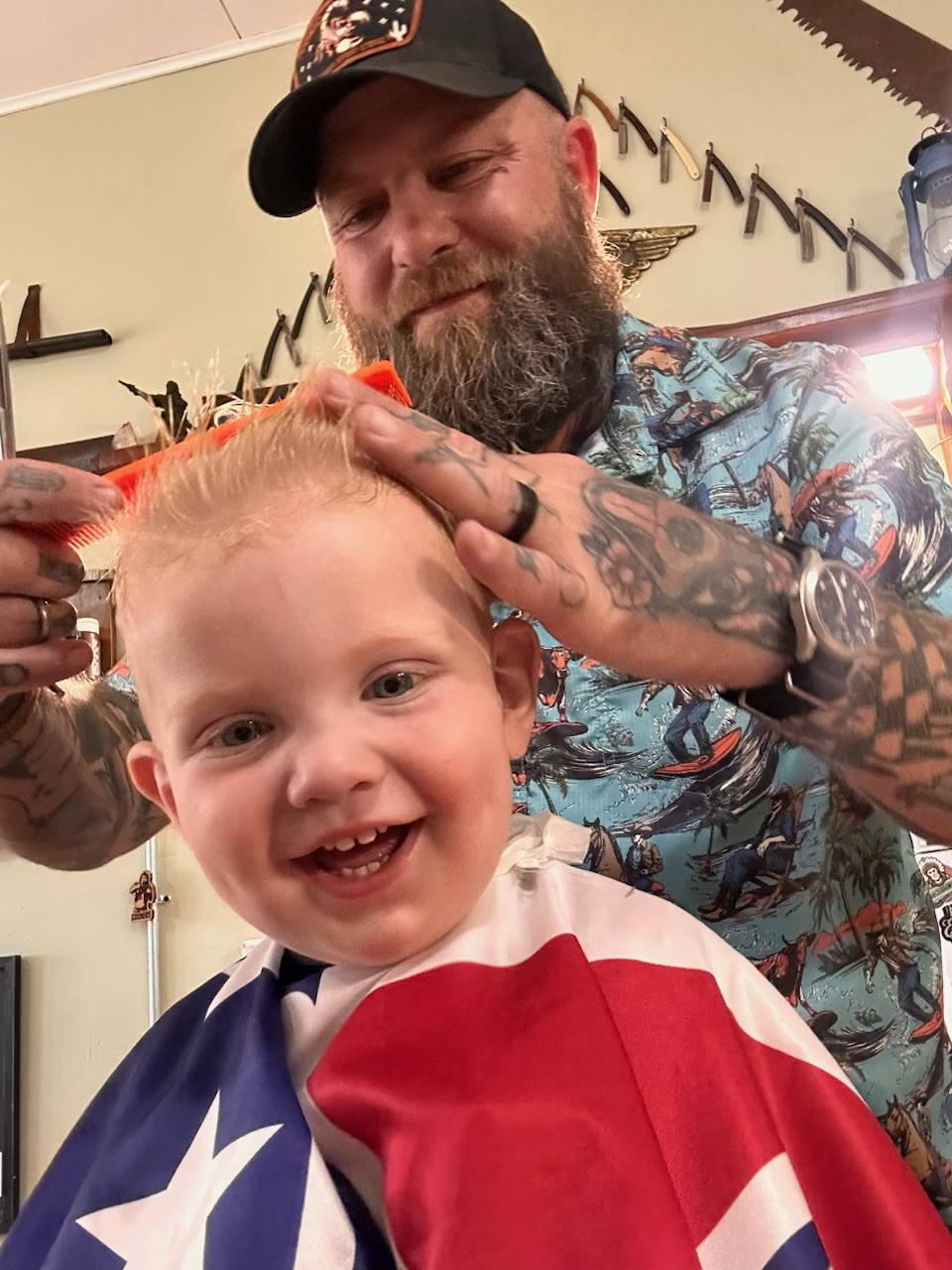 Tony giving his son a haircut with patriotic cape